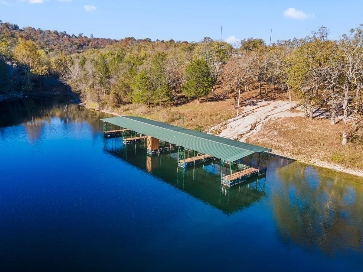 A peaceful lakeside dock surrounded by calm water and lush trees. The dock extends out onto the lake, providing a perfect spot for fishing, boating, or relaxing by the water's edge. The tranquil setting is ideal for enjoying sunrises or quiet afternoons.
