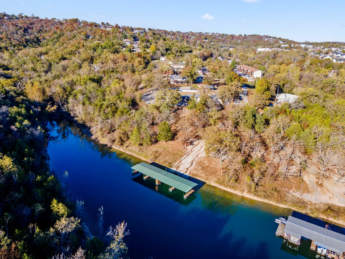 A peaceful dock juts out over calm water with green hills and trees lining the shore. The dock is perfect for early morning fishing or simply soaking in the serenity of the lakeside setting.