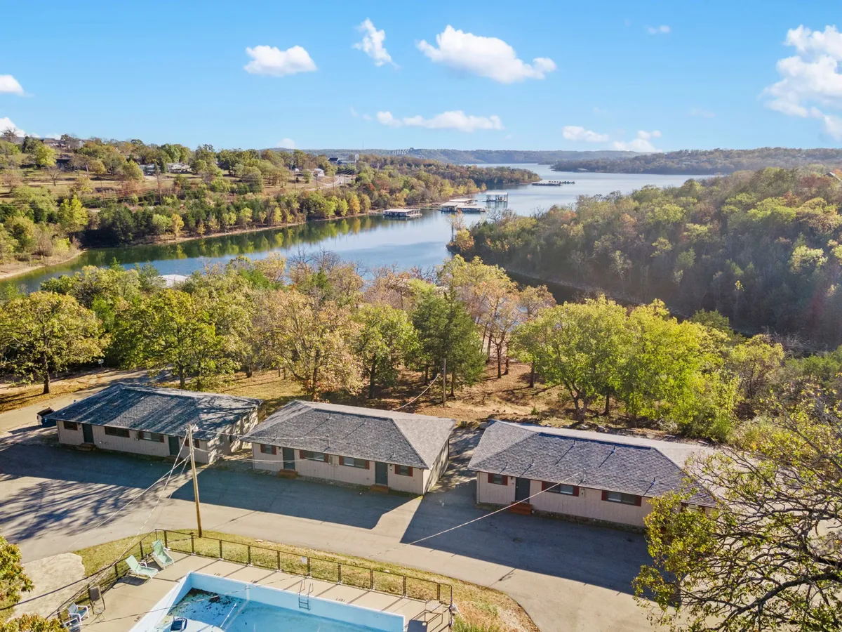 This image showcases a scenic view of Table Rock Lake with cabins nestled among trees and a sparkling swimming pool in the foreground. The area exudes a relaxing, family-friendly atmosphere, inviting guests to swim, boat, hike, or enjoy a lakeside picnic.