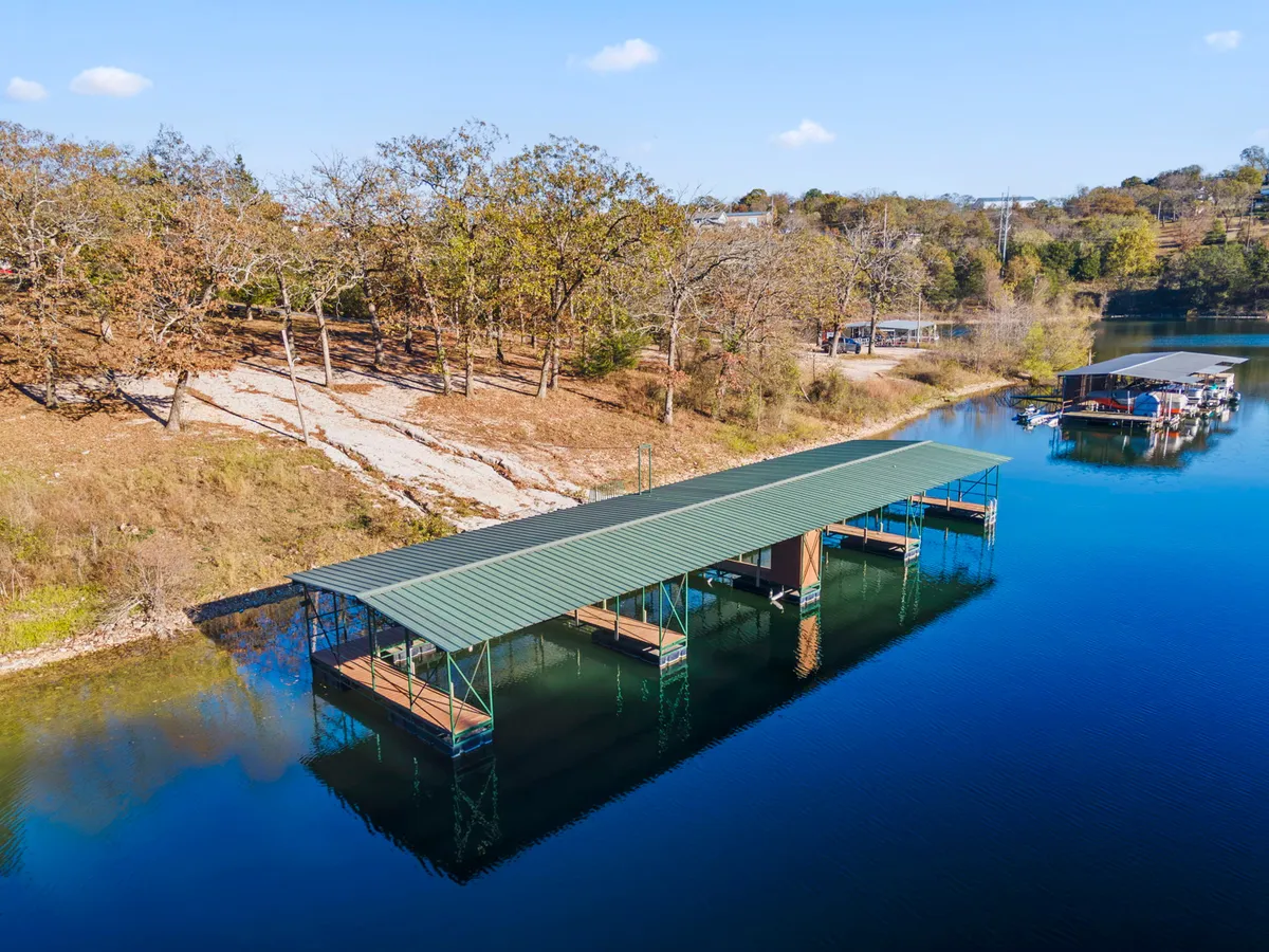 A peaceful boat dock stretching over calm water with surrounding trees, evoking early mornings or sunset adventures. The simplicity and tranquility of the scene suggest opportunities for lakeside exploration, picnics, and quiet moments with a pet.