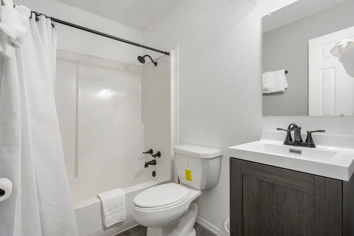 The bathroom is shown with a clean shower area, vanity with a sink, and toilet, all arranged in a functional and inviting way. The space is well-lit and practical, illustrating the convenience for post-adventure refreshes.