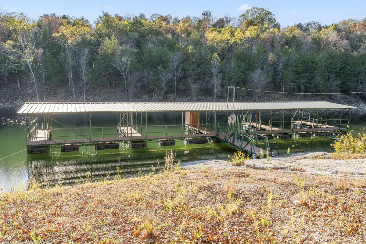 A peaceful boat dock stretches over calm waters, surrounded by lush greenery. The inviting dock is ideal for boating, fishing, or simply soaking in the tranquil beauty of lakeside mornings and sunsets.